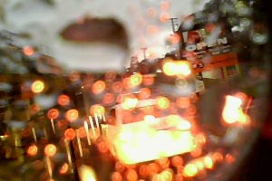 Car break light reflected in water on lens